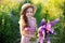 Close up portrait of a smiling little girl in a straw hat and with a large bouquet of lupins. A child girl in a field of lupines.