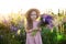 Close up portrait of a smiling little girl in a straw hat and with a large bouquet of lupins. A child girl in a field of lupines.