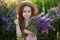 Close up portrait of a smiling little girl in a straw hat and with a large bouquet of lupins. A child girl in a field of lupines.