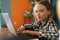 Close-up portrait of smiling pretty elementary child girl sitting at desk with laptop at home looking at camera.