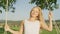 CLOSE UP,PORTRAIT: Smiling woman swaying on a rope swing in nature by herself.