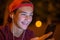 Close-up portrait of a smiling young man with a smartphone, in street at night.  Happy teenage boy is using mobile phone, outdoors