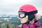 Close up portrait of snowboarder woman at ski resort wearing helmet and goggles with reflection of mountains.