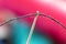 A close up portrait of some sewing thread put through the hole of a needle. The yarn is black and the background is out of focus