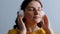 Close up portrait of stylish young girl listening to music with closed eyes and enjoying melody on gray background