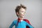 Close-up portrait superhero kid. Dreamy boy in red cape against a gray wall, success, motivation