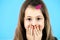 Close up portrait of surprised cute girl with pink hairpin on blue background