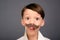 Close up portrait of surprised funny schoolboy holding paper mustache