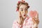 Close-up portrait of surprised or impressed young girl in hair-curlers and eye patch mask looking at heart-shaped mirror