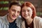 Close up portrait of teenage couple smiling at camera while listening to music together using same pair of earphones