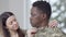 Close-up portrait of thoughtful African American military man looking away as blurred Caucasian young woman adjusting