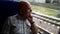 Close-up portrait of a thoughtful elderly grandfather in a checked shirt, who is riding on a train and looks out the