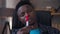 Close-up portrait of thoughtful serious young man looking at pen thinking. Intelligent concentrated African American