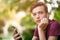 Close-up portrait of a thoughtful unhappy teenage boy with smartphone, outdoors.  Sad teenager with mobile phone looks away, in