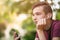 Close-up portrait of a thoughtful unhappy teenage boy with smartphone, outdoors.  Sad teenager with mobile phone looks away, in