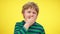 Close-up portrait of tired little boy yawning at yellow background. Exhausted Caucasian blond child with sad facial