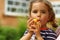 Close up portrait of a toddler girl blowing a toy wooden whistle