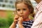 Close up portrait of a toddler girl blowing a toy wooden whistle