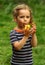 Close up portrait of a toddler girl blowing a toy wooden whistle