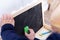 A close up portrait of a toddler scribbling, drawing or doodling a bit on a chalkboard. The child is wiping the blackboard and has