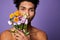 Close up portrait of transgender man looking camera with flowers in hand. Handsome sensual american