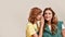 Close up portrait of two attractive young girls, twin sisters in casual wear telling secrets, gossiping, standing