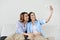 Close up portrait of two excited girlfriends with mobile phones, laughing. Happy joyful female friends resting at home, enjoying