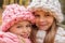 Close-up portrait of two happy smiling girls in hats and scarves of rough hand-knitted christmas winter