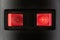 A close up portrait of two red on off safety switches of a power strip with a light in them to indicate the power sockets of the