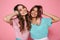 Close-up portrait of two smiling woman dressed like children touching their hair, looking at camera