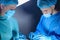 Close-up portrait of two surgeons operating in an operating room with instruments. In sterile medical surgical special clothing