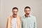 Close up portrait of two young angry twin brothers shouting and looking at camera while posing together isolated over