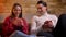 Close-up portrait of two young caucasian friends near sofa drinking tea and talking with each other in cosy home