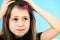 Close up portrait of upset and pensive little girl with cute pink hairpin on blue background