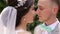 Close-up portrait of wedding couple touching noses outdoors.