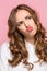 Close-up portrait of a woman doing a fish mouth expression, over a pink background