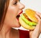 Close up portrait of woman face biting hamburger.