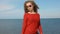 Close up portrait of woman in fashion trendy sunglasses running hand through curly hair blowing in wind by sea on beach