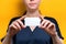 Close-up portrait of a woman holding a white business card. Mock up. Yellow background. Copy space