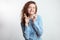 Close up portrait woman with long curly red hair standing with crossed fingers.