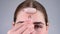 Close-up portrait of a woman uses a quartz roller massager to smooth wrinkles on her forehead.