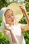 Close-up portrait of woman wearing straw hat enjoying summer sun. Pattern of shadows falling on her face