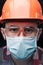 Close-up portrait of a worker in a helmet, mask and safety glasses.