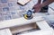 Close up portrait of workers hands at carpenter workspace refining the surface of wood board using sand paper grinder