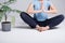 Close-up of portrait of yoga trainer girl sitting in lotus position on a white background next to a green flower