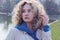 Close up portrait of a youg girl looking to the side. Cute curly girl outdoor.