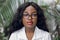 Close up portrait of young African woman, scientist, botanist, agronomist, wearing glasses and white lab coat, posing to