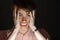 Close-up portrait of young anger man in horror clutching his head with his hands. Isolated on black background and