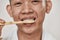 Close up portrait of young asian man with problematic skin brushing his teeth isolated over white background. Beauty