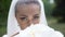 Close-up portrait of the young attractive brunette bride smelling the wedding bouquet of white flowers and looking in